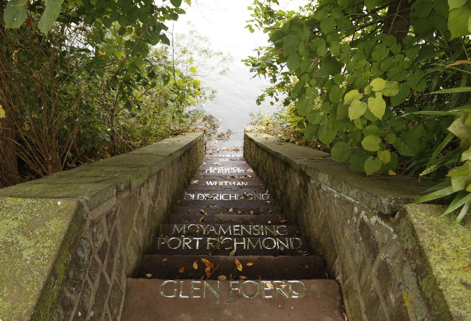 A stone stairway leading to a river has the names of Philadlephia neighborhoods on the steps.
